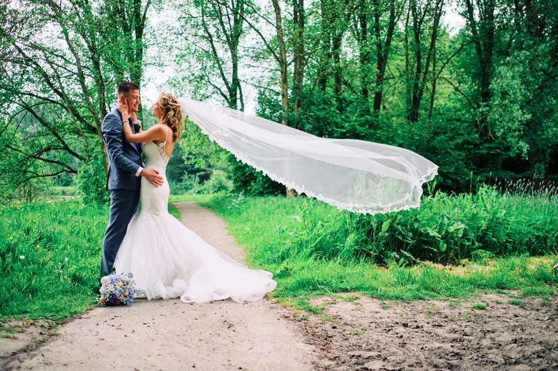 Lotte en Daniel lopen over een zandpad, de sluier in de wind
