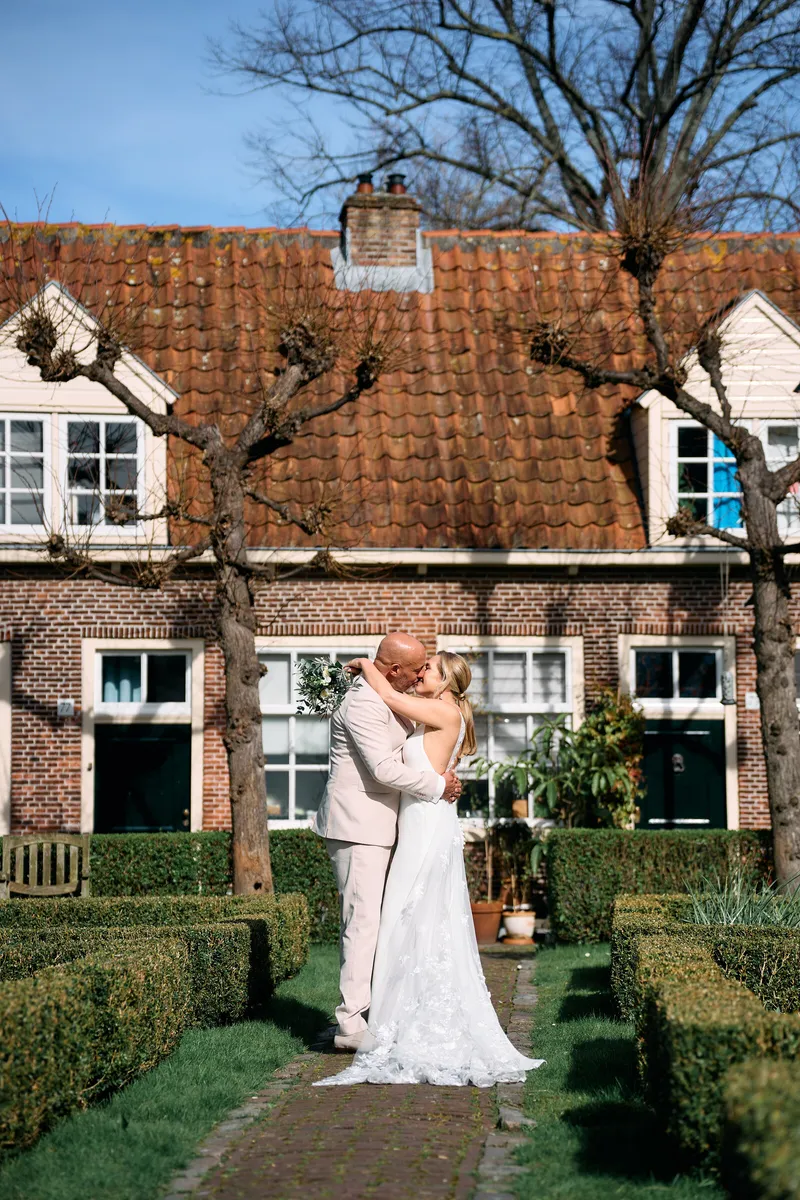 Danitsja en Brian in een hofje met lage hagen voor een huis met rode pannen