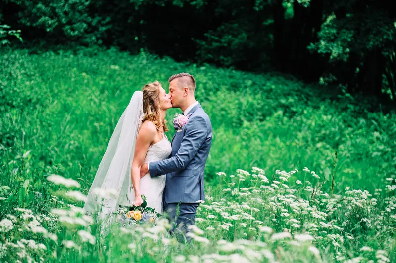 Lotte en Daniel kussen in het hoge gras met witte bloemen