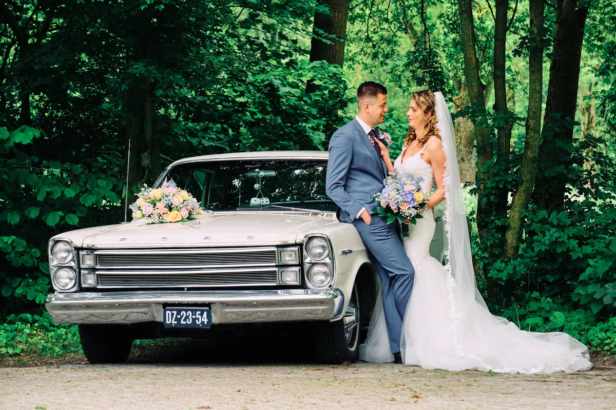 Lotte en Daniel bij de witte oldtimer tussen de bomen