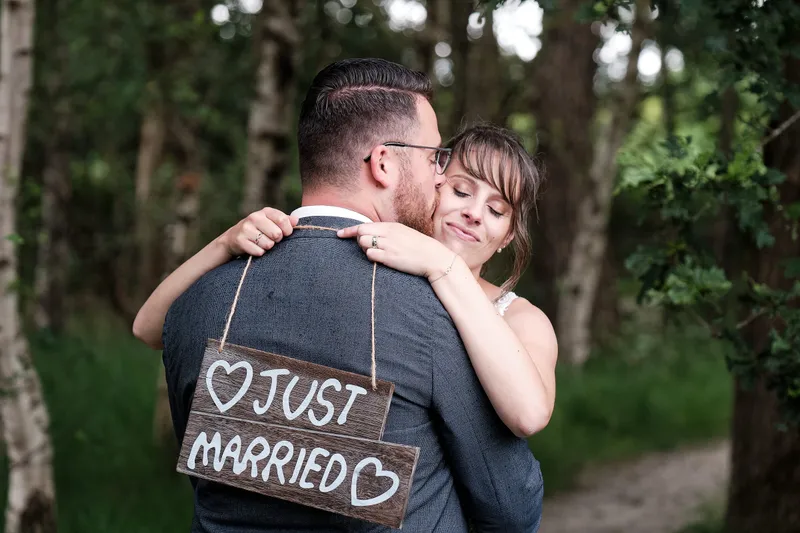 Milou omhelst Barry van achteren, hij houdt een Just Married-bordje vast