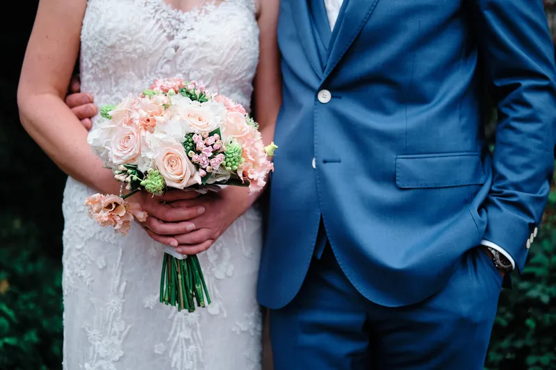 Het boeket met roze bloemen tegen het blauwe pak