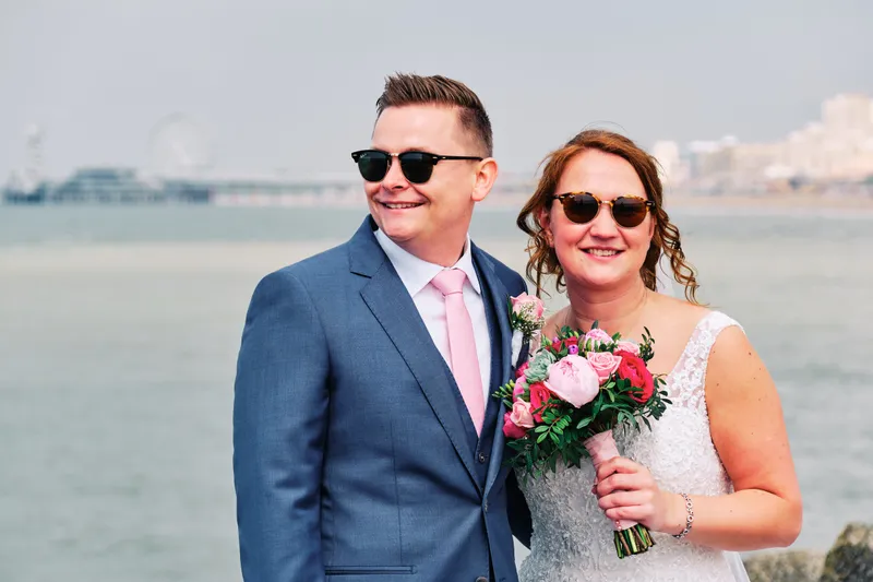 Stefan en Victoria lachen met hun zonnebril op, de zee erachter