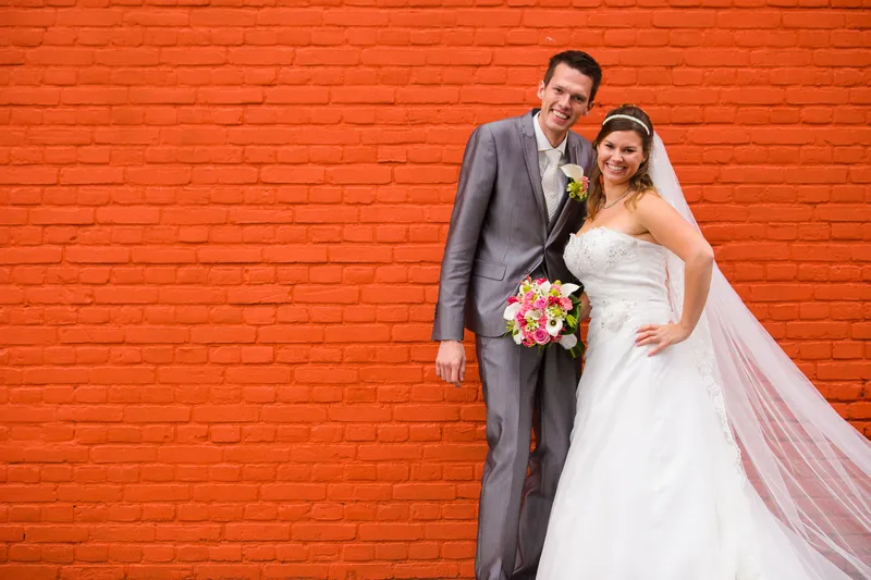 Mark en Annika voor een felle oranje bakstenen muur