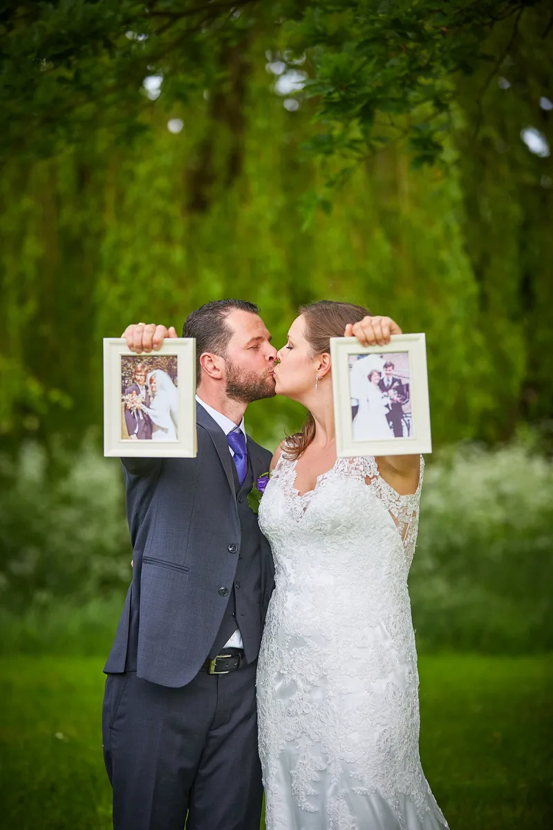 Robbert en Nadine kussen achter twee ingelijste foto’s