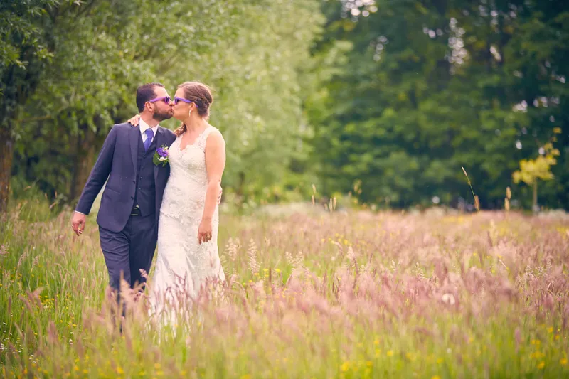 Robbert en Nadine kussen in het hoge gras met roze bloemen