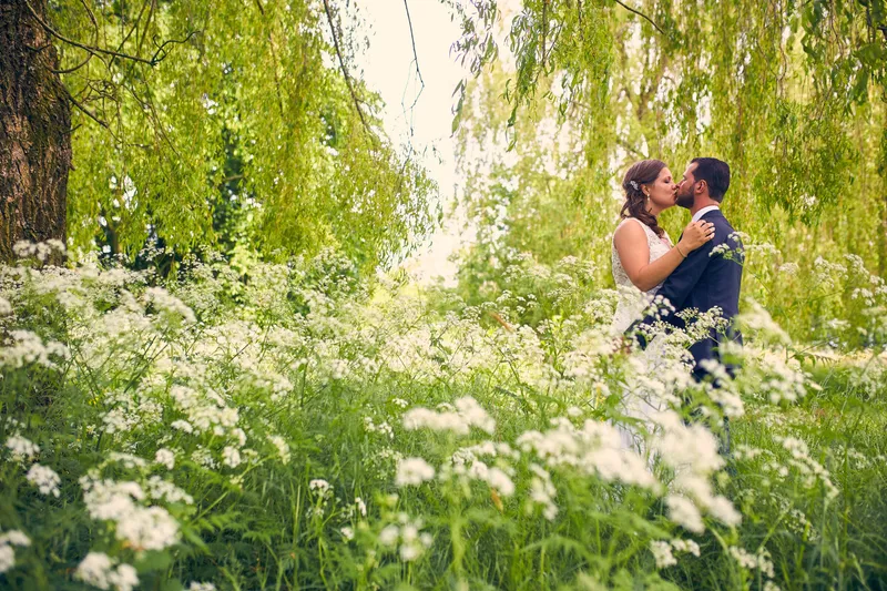 Robbert en Nadine klein tussen de witte bloemen onder de wilgen