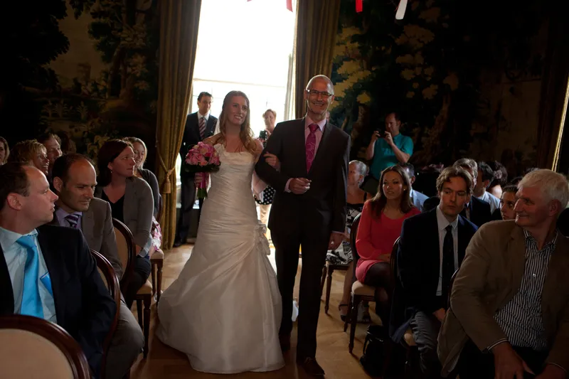 Loes loopt met haar vader door het middenpad van de trouwzaal