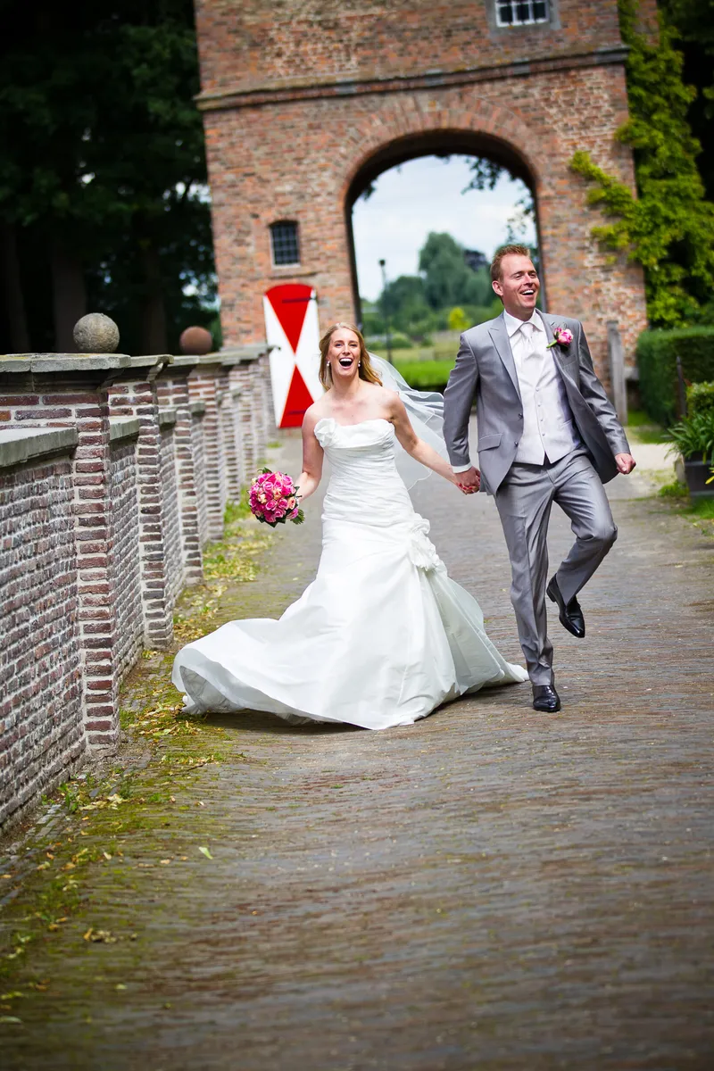Loes en Jan rennen hand in hand over het pad bij de poort van Slot Zuylen