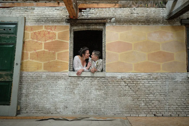 Regina en haar zoon kijken door een raam in een geel beschilderde muur