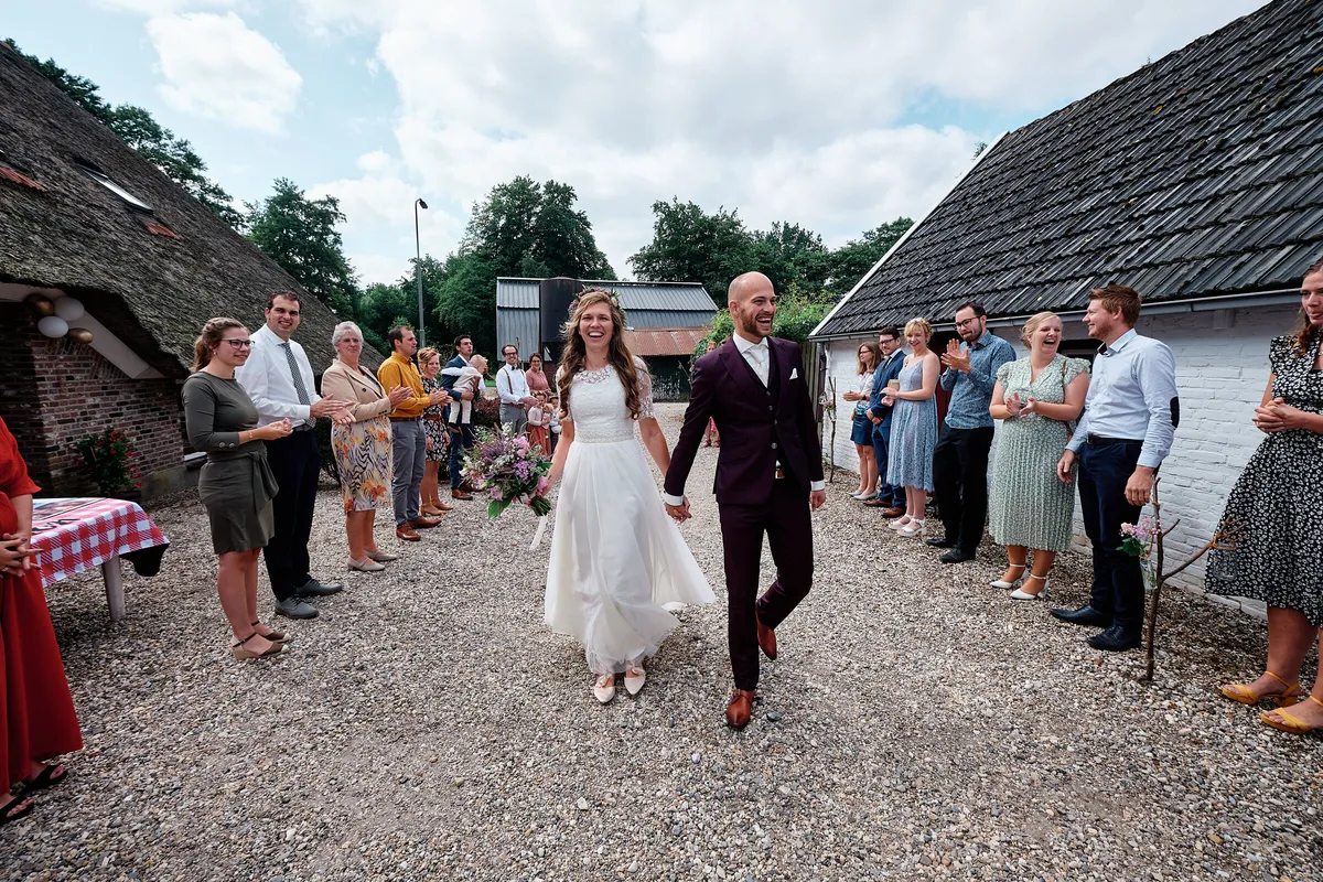 Simon en Mariëth lopen over het grind langs de rieten boerderij op het terrein van de familie