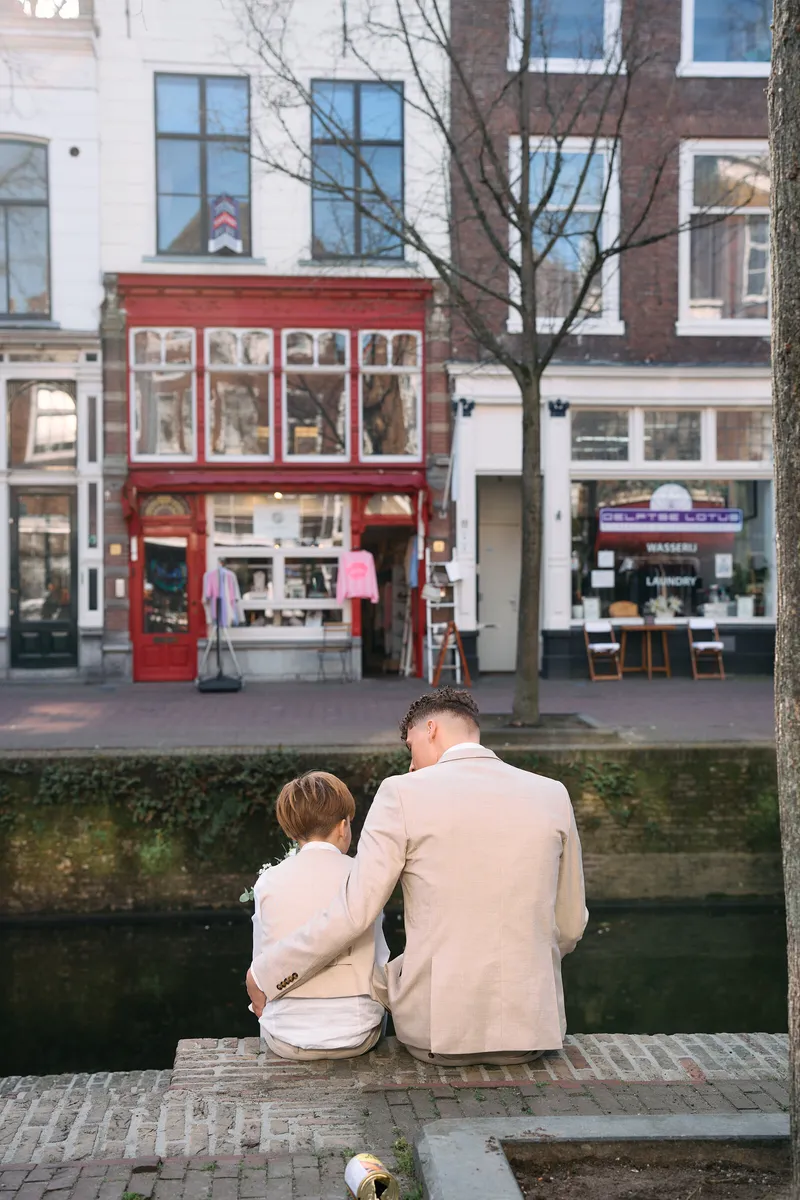 Brian zit met zijn zoon op de rand van de gracht, met de gevels aan de overkant