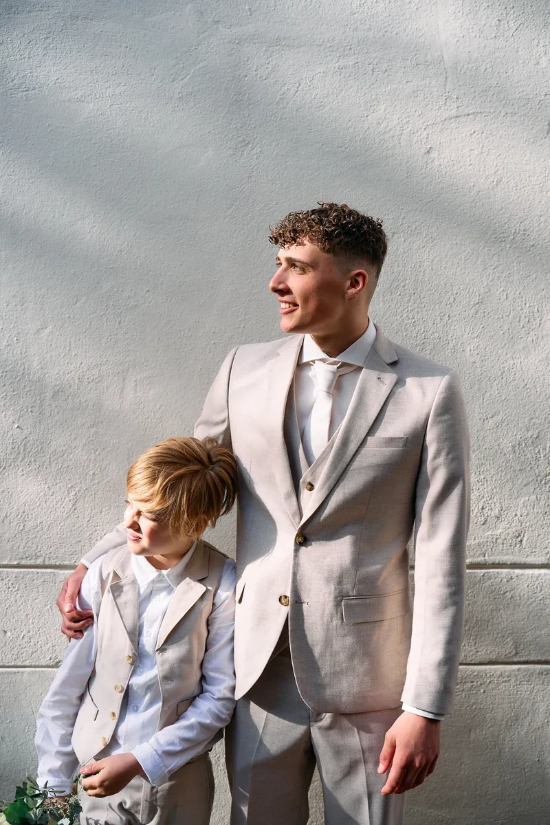 De oudste zoon met zijn kleine broertje tegen een witte muur