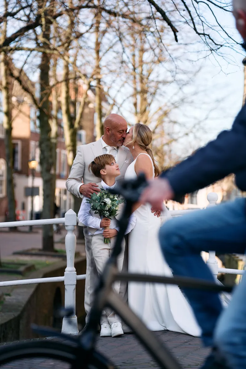 Danitsja en Brian kussen op een brug terwijl er een fietser langskomt