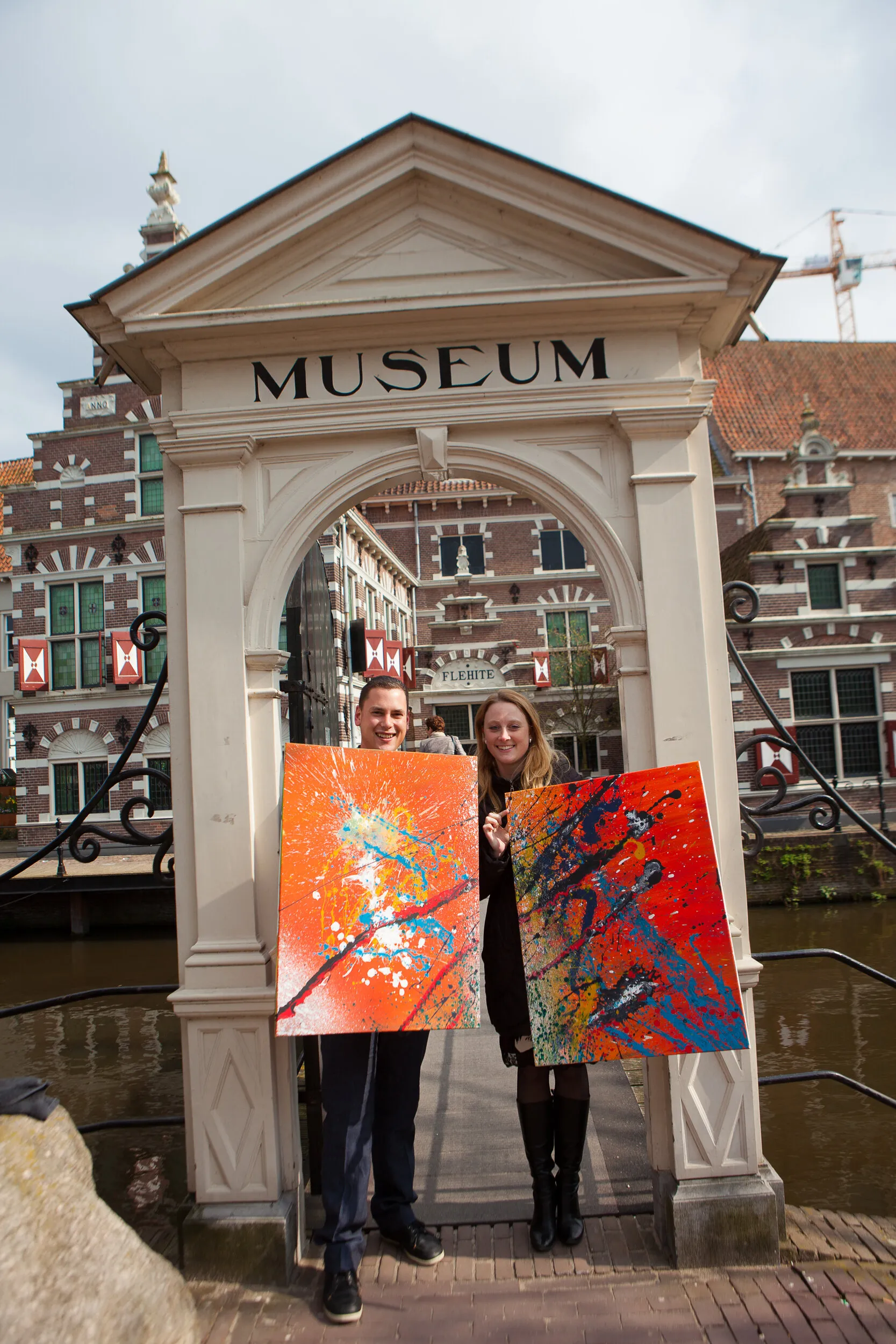 Carolien en Jelle met twee kleurrijke doeken onder de poort van Museum Flehite