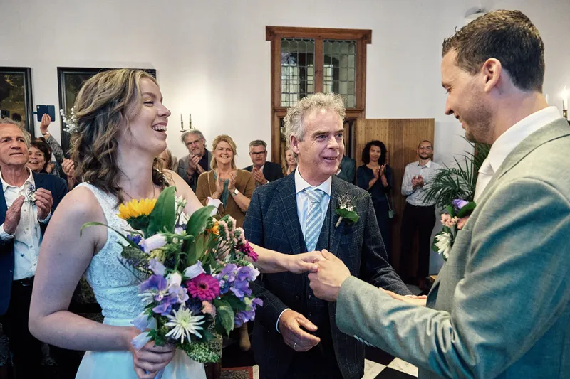 Renske en Tijmen lachen tijdens de ceremonie in de trouwzaal van het stadhuis