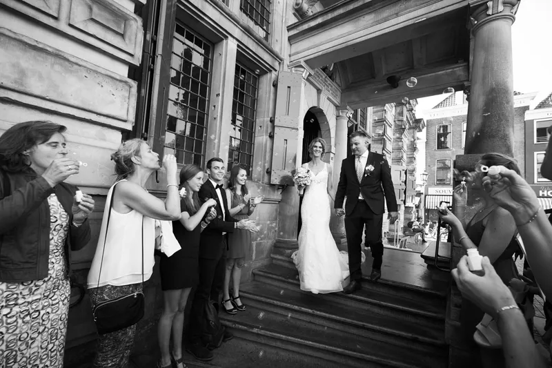 Zwart-wit: Ingrid en Richard komen de trap van het stadhuis af tussen de juichende gasten