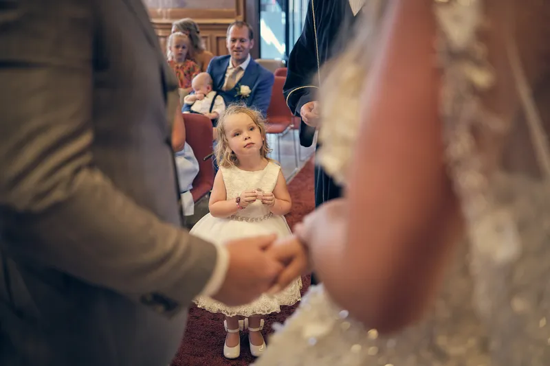Jordy schuift de ring om, met een meisje in een witte jurk op de achtergrond