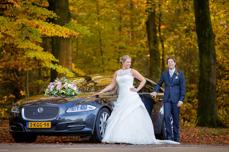 Ingeborg en Martijn bij de Jaguar, met het bos erachter