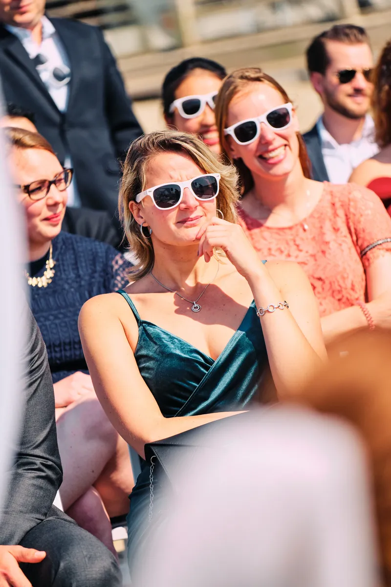 Gasten met de witte zonnebrillen van het bruidspaar bij de ceremonie
