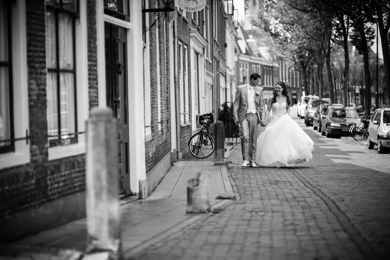 Zwart-wit: het bruidspaar loopt door een oude straat
