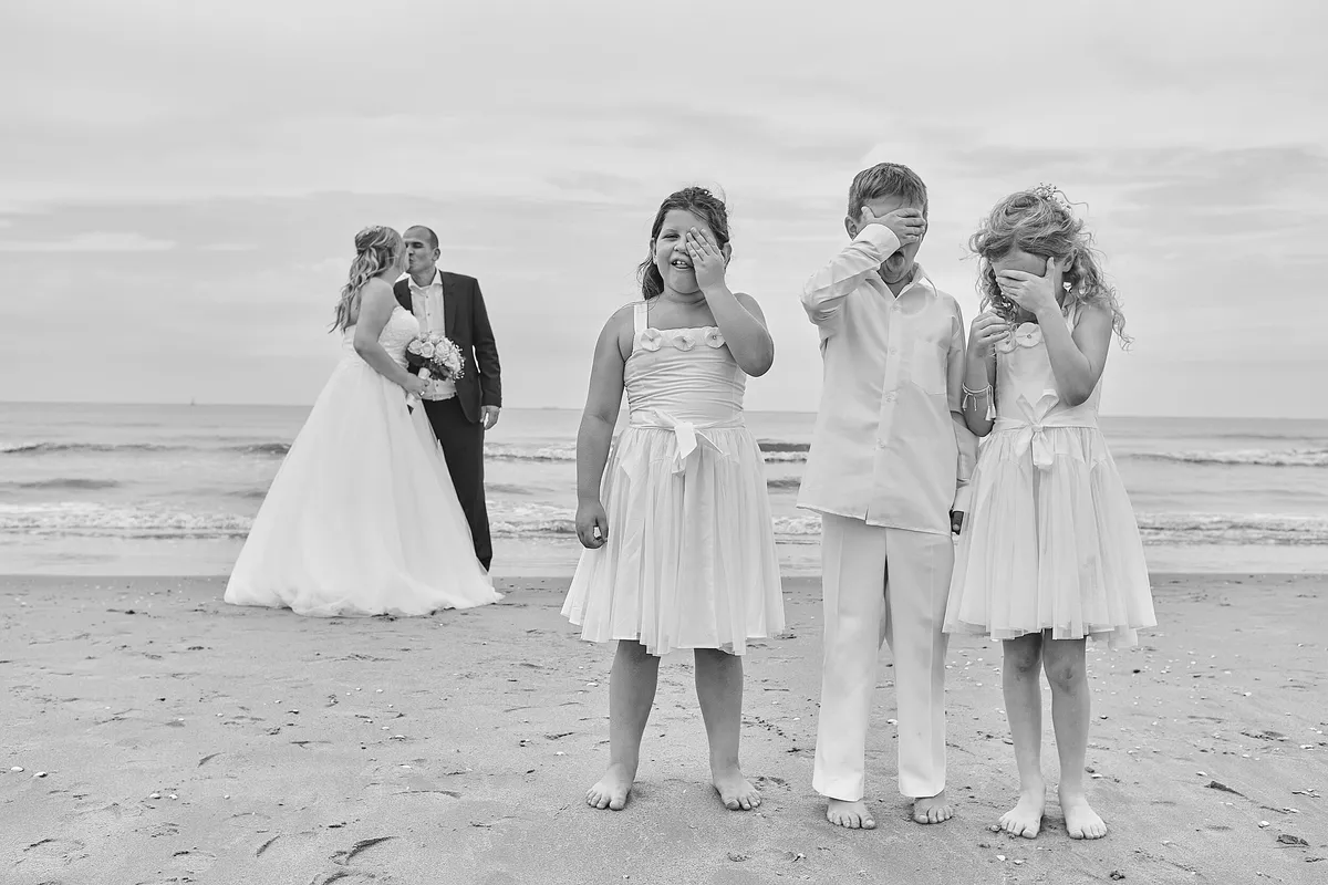 Zwart-wit: Vanessa en Manuel op het strand, de kinderen houden hun handen voor hun gezicht
