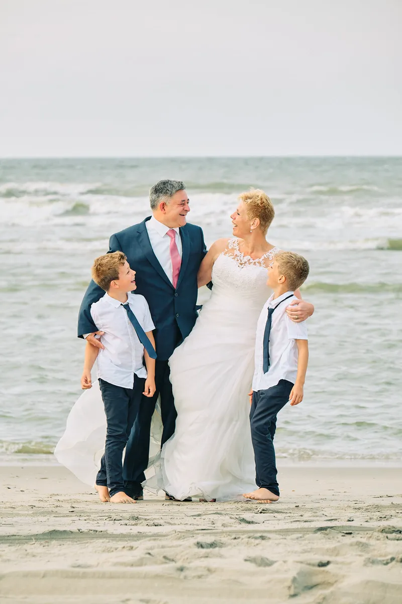 Helen en Burt met hun zoons op het strand, de zee erachter