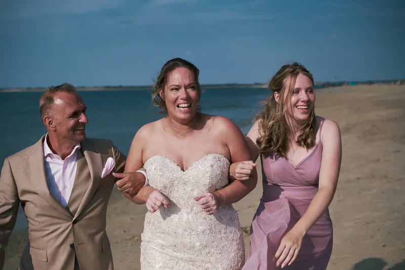 Mirjam en Jorg lopen lachend met de dochter van Mirjam over het strand