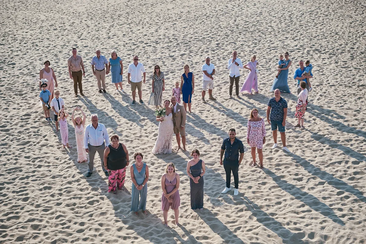 Alle gasten staan in de vorm van een hart op het strand