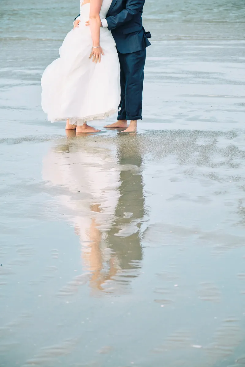 Helen en Burt in het natte zand, met hun spiegelbeeld