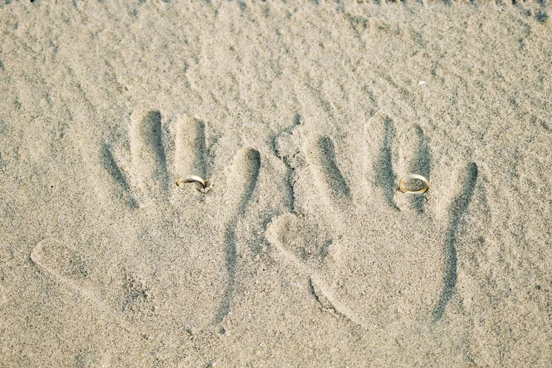 Handafdrukken in het zand met de twee trouwringen