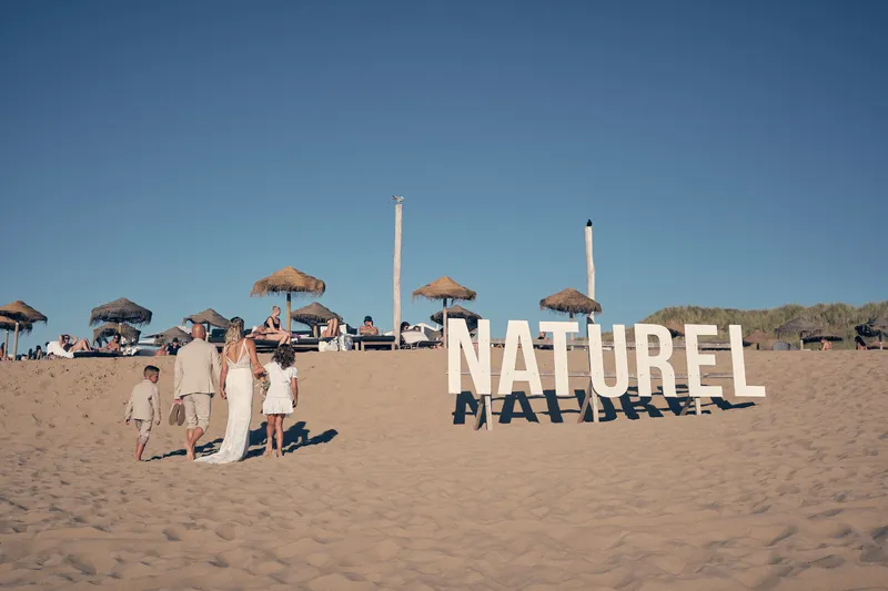 De grote letters Naturel op het strand, met het gezin