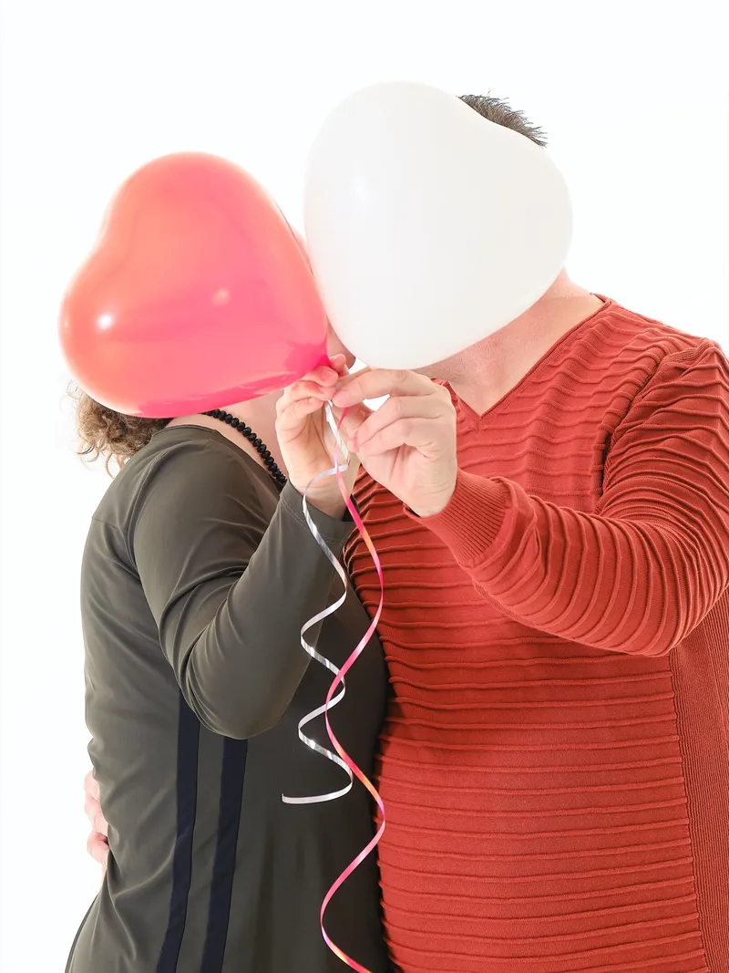 Stel houdt rood-witte hartballonnen voor hun gezicht