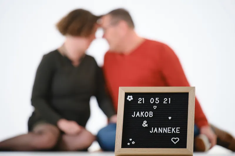 Jakob en Janneke zitten voorhoofd tegen voorhoofd op de vloer, voor hen een letterbord met hun trouwdatum
