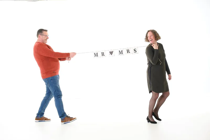 Een koppel trekt lachend een ‘Mr & Mrs’-slinger tussen zich uit
