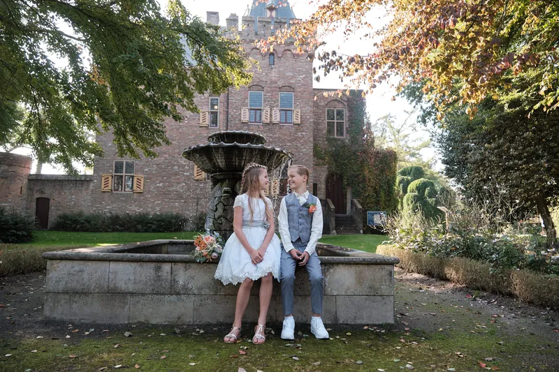 Twee meisjes in witte jurkjes bij de fontein voor Kasteel Sypesteyn