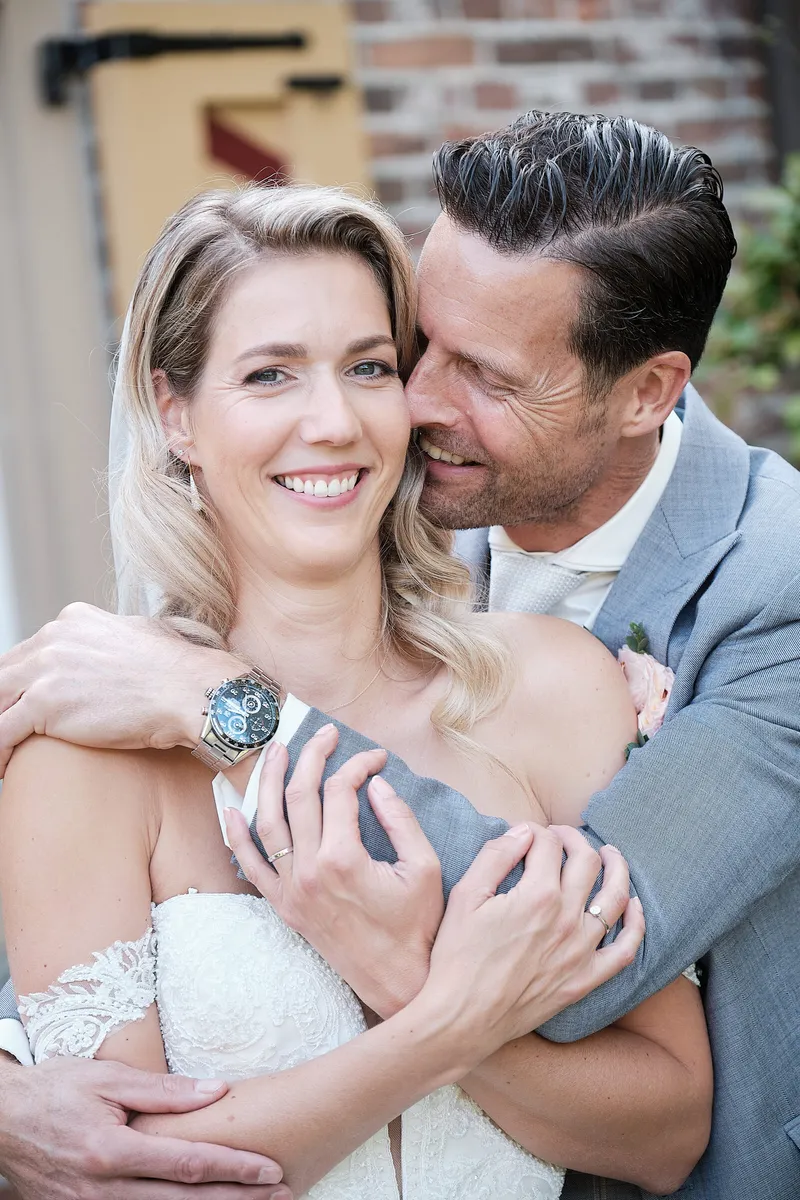Lucinda lacht naar de camera, Carlo omhelst haar van achteren