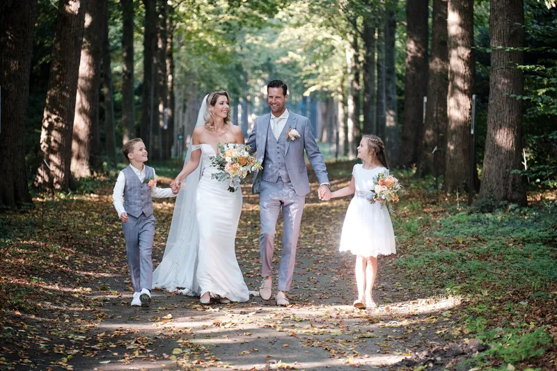 Lucinda en Carlo lopen met de kinderen tussen de herfstbladeren
