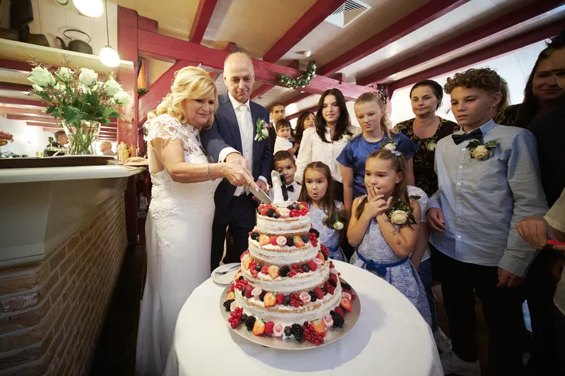 Jopie en Cees snijden de taart aan, de kleinkinderen staan eromheen