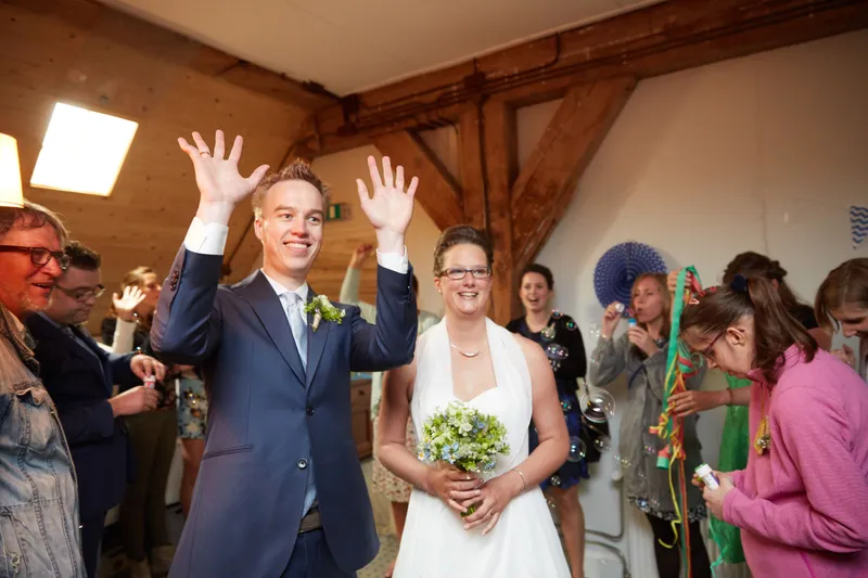 Coen steekt zijn handen in de lucht, Marjolein lacht met het boeket