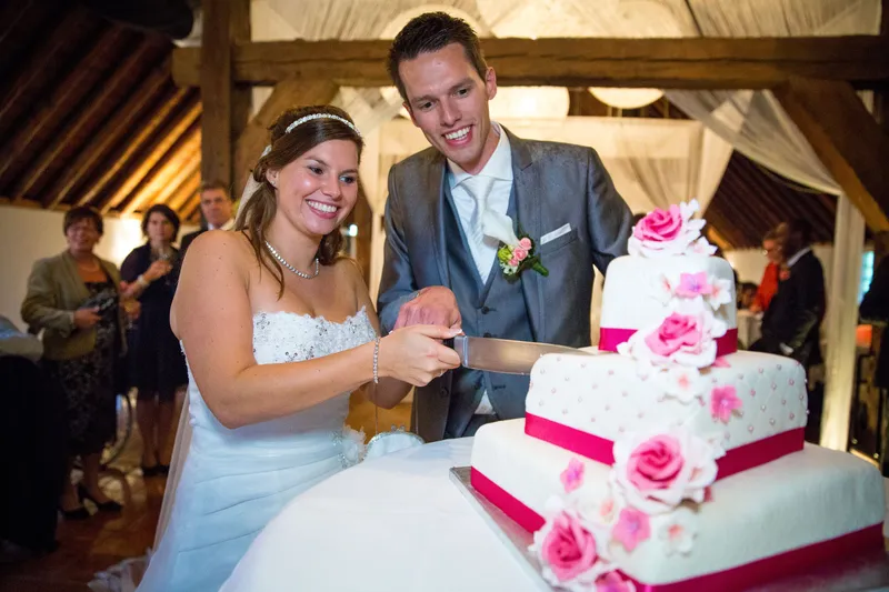 Mark en Annika snijden de taart met roze rozen aan