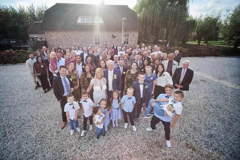 De groepsfoto met alle gasten op het grind voor de boerderij
