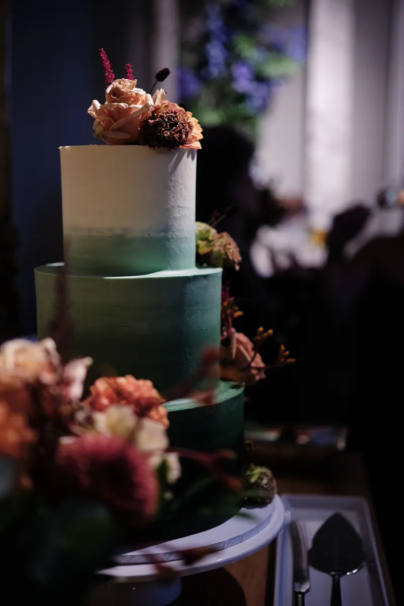 De groene bruidstaart met herfstbloemen in een donkere hoek