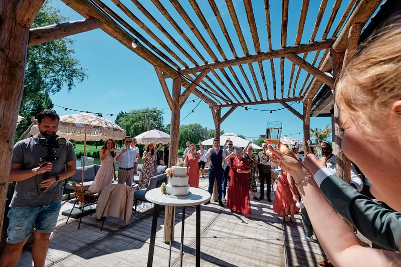 Gasten onder de pergola kijken naar de taart