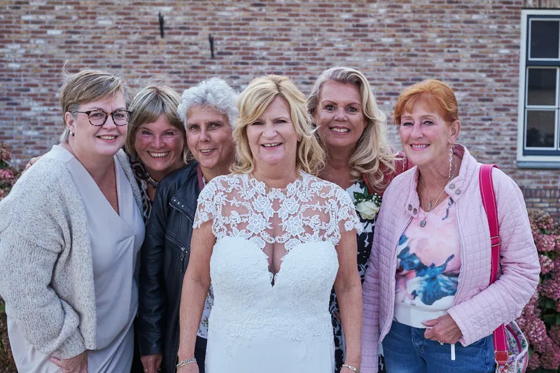 Jopie met gasten voor de bakstenen muur