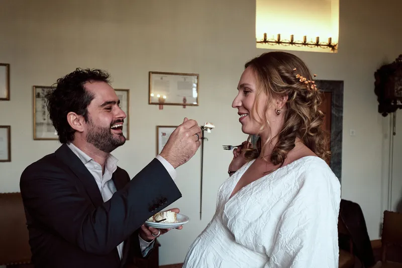 Raphaël voert Anouk een stukje taart, ze lachen allebei