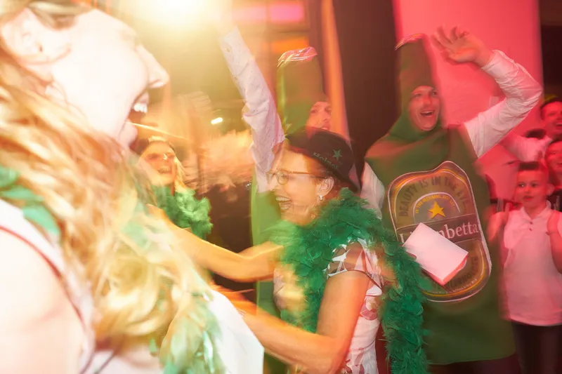 Een gast in een biervat-pak met een groene boa op de dansvloer