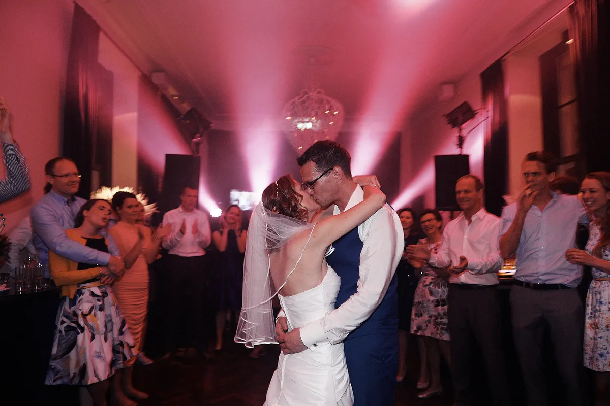 Femke en Arjan kussen op de dansvloer in roze licht