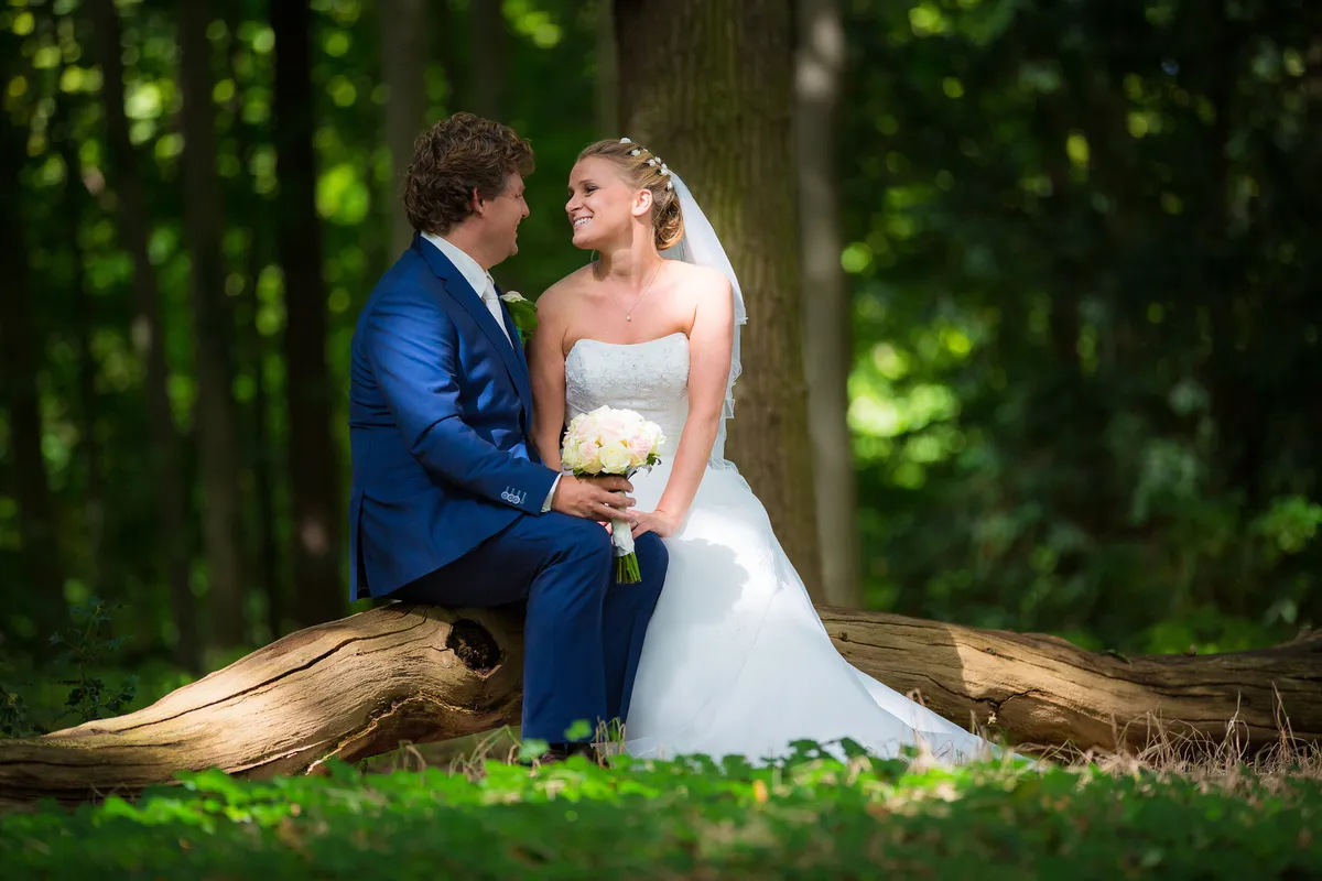 Liselotte en Matthijs zitten op een boomstam tussen de bomen