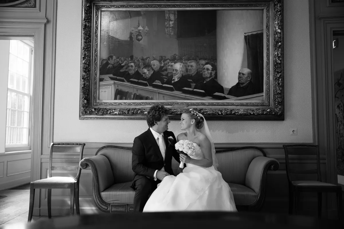 Zwart-wit: Liselotte en Matthijs op een bank onder een groot schilderij